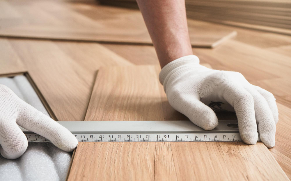 Laminatboden in Holzoptik wird bei der Verlegung mit einem Zollstock ausgemessen und für den passgenauen Zuschnitt vorbereitet.