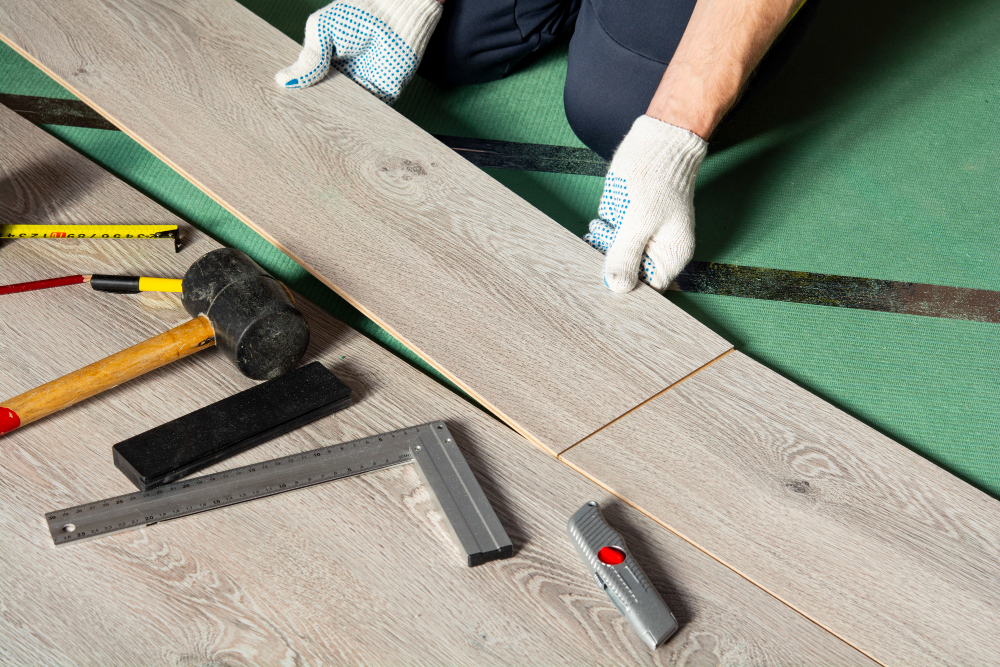 Handwerker verlegt Vinylboden mit Werkzeug